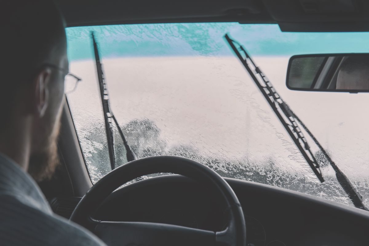 Man driving in the rain with poor visibility due to windshield wiper scratches
