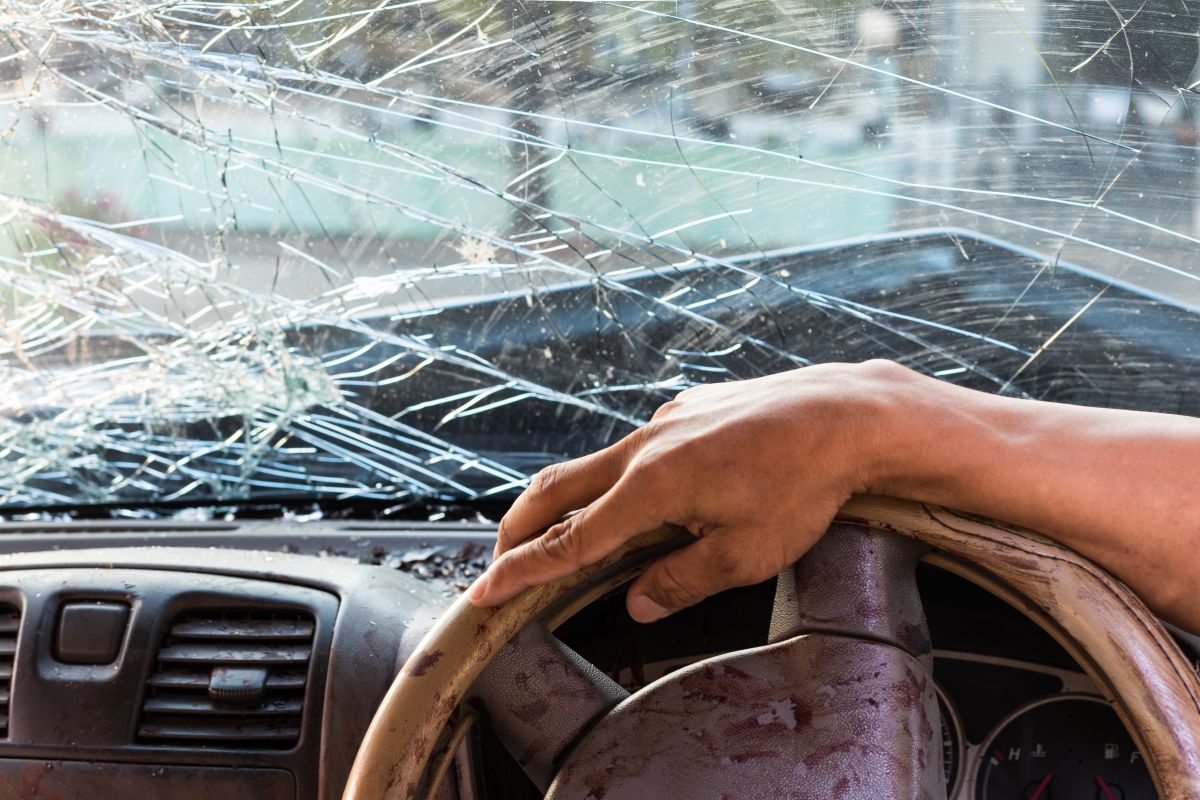 Driver’s view through a cracked windshield while driving, highlighting visibility issues and safety risks associated with damaged auto glass.
