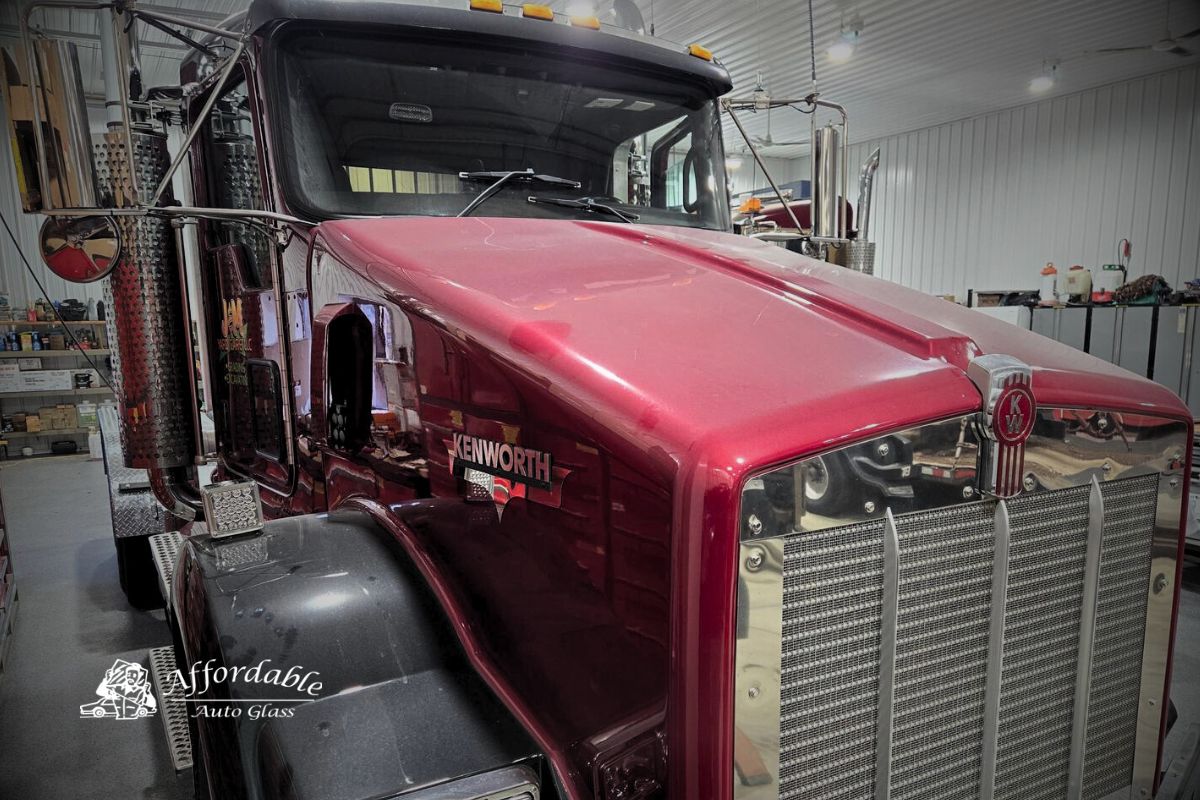 Red Kenworth semi truck inside a shop after professional windshield replacement by Affordable Auto Glass Wisconsin.