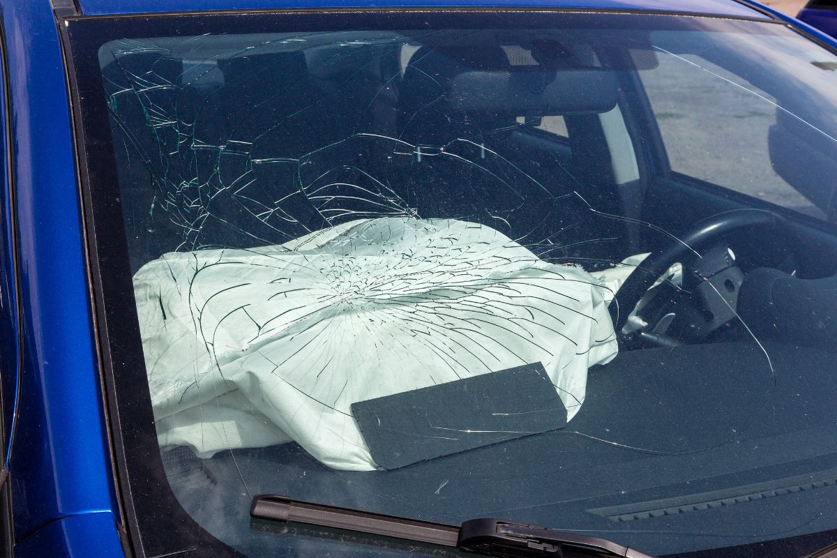 Cracked windshield on a vehicle, illustrating how windshield damage can affect airbag deployment and compromise passenger safety.