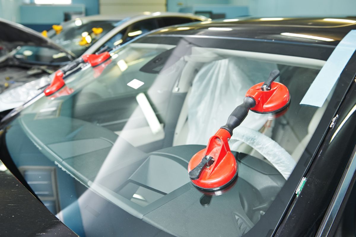 Windshield installation in progress using suction tools, demonstrating the importance of proper adhesive curing time after windshield replacement.