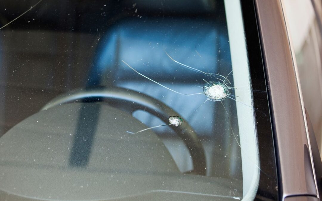 Close-up of a windshield with visible cracks under strong sunlight, illustrating the damaging effects of heat on auto glass.
