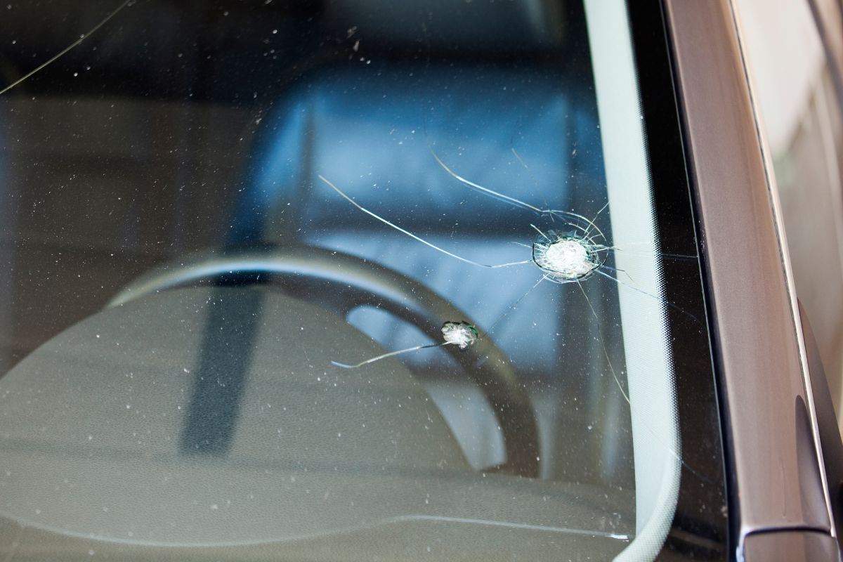 Close-up of a windshield with visible cracks under strong sunlight, illustrating the damaging effects of heat on auto glass.