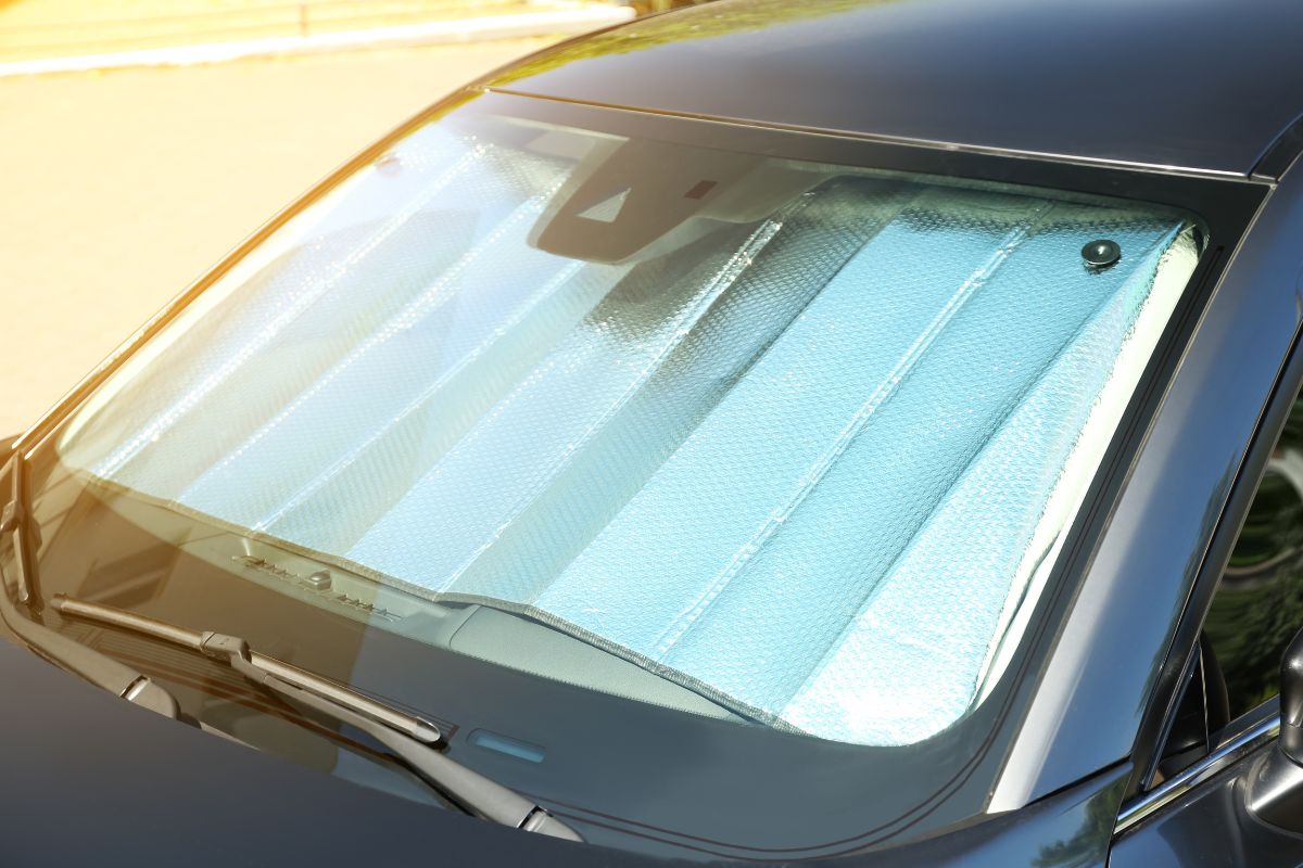Close-up of a parked car with a reflective sunshade on the windshield to prevent heat buildup and protect against temperature-related glass cracks.