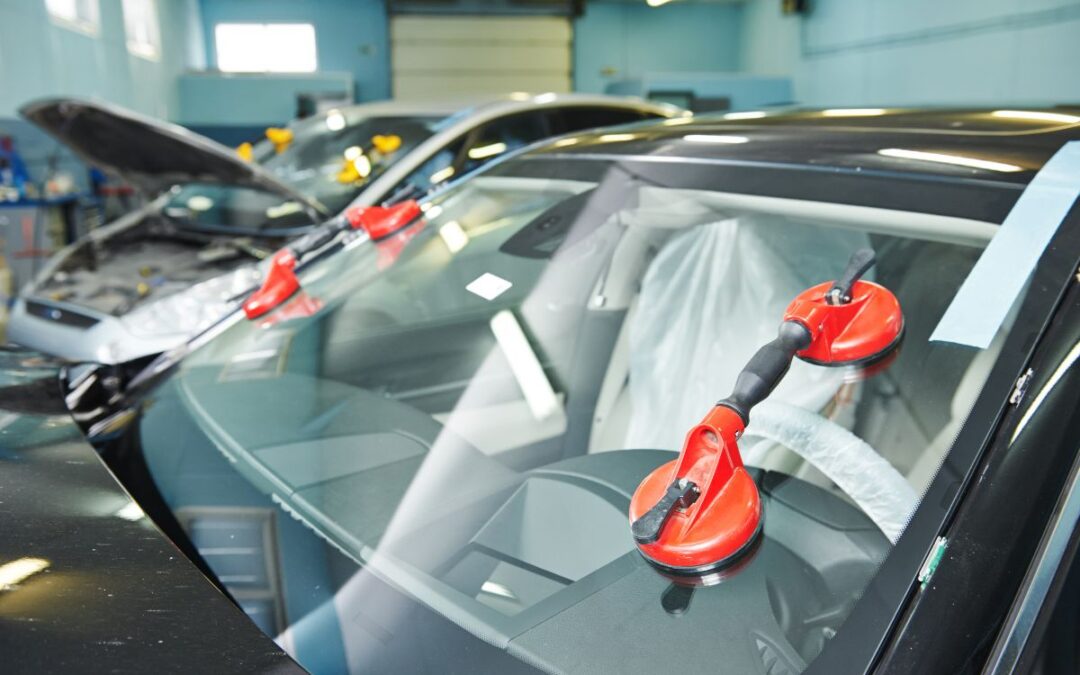 Technicians using suction tools for windshield replacement — best way to extend windshield life in a professional auto glass repair shop.