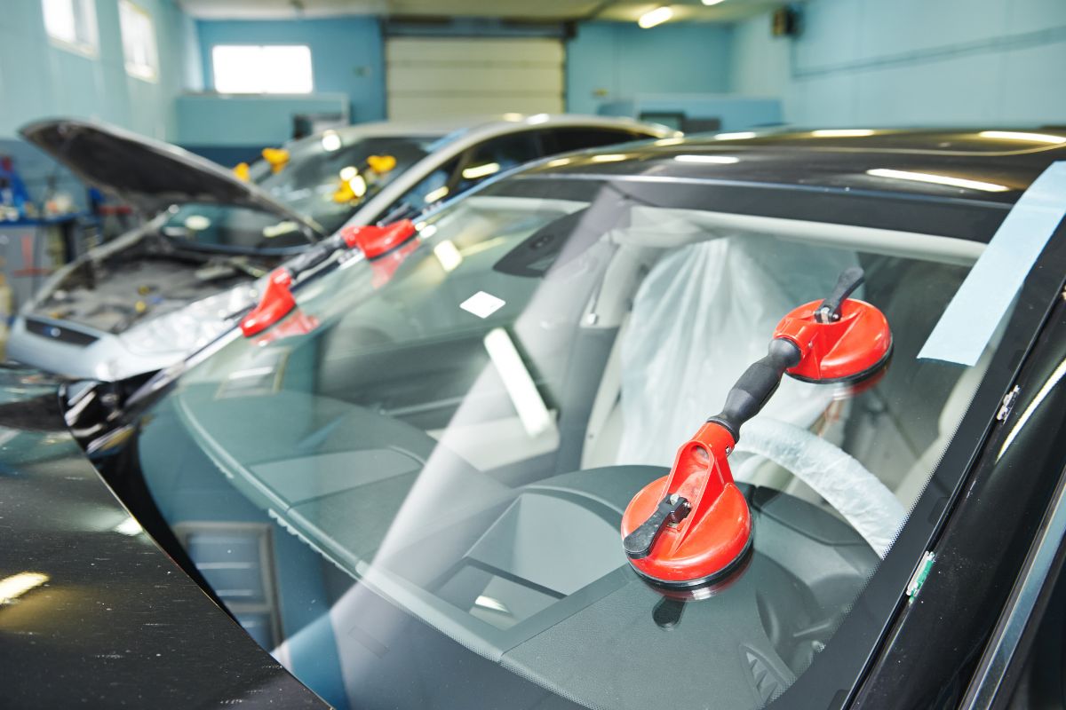 Technicians using suction tools for windshield replacement — best way to extend windshield life in a professional auto glass repair shop.