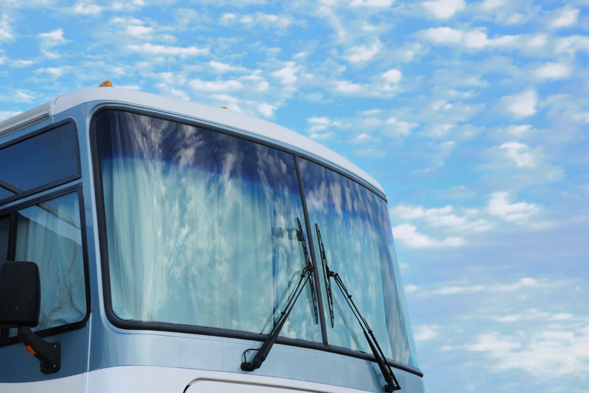 arge RV windshield with dual wipers reflecting a blue sky with clouds, representing RV windshield replacement services in Lake Country, Wisconsin.