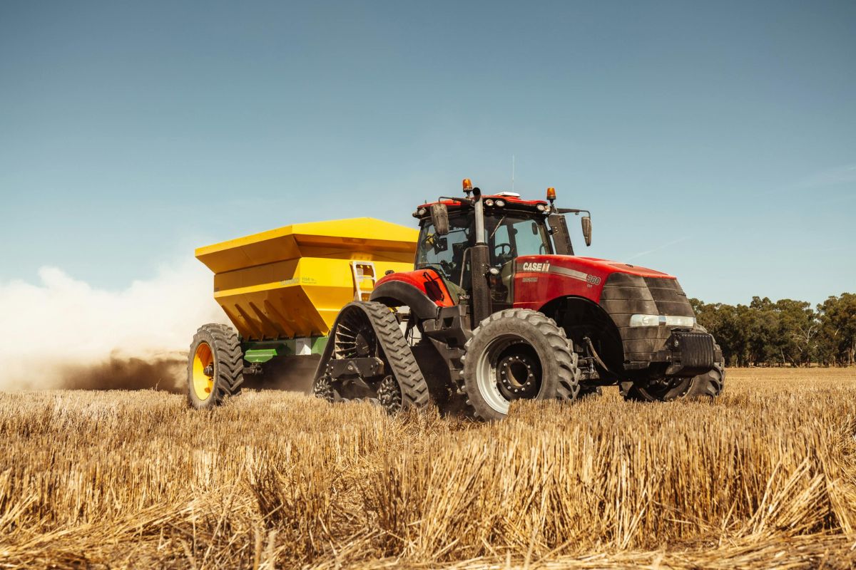 Red tractor hauling a yellow trailer on a Wisconsin farm field, showing the type of machinery that may need heavy equipment windshield replacement
