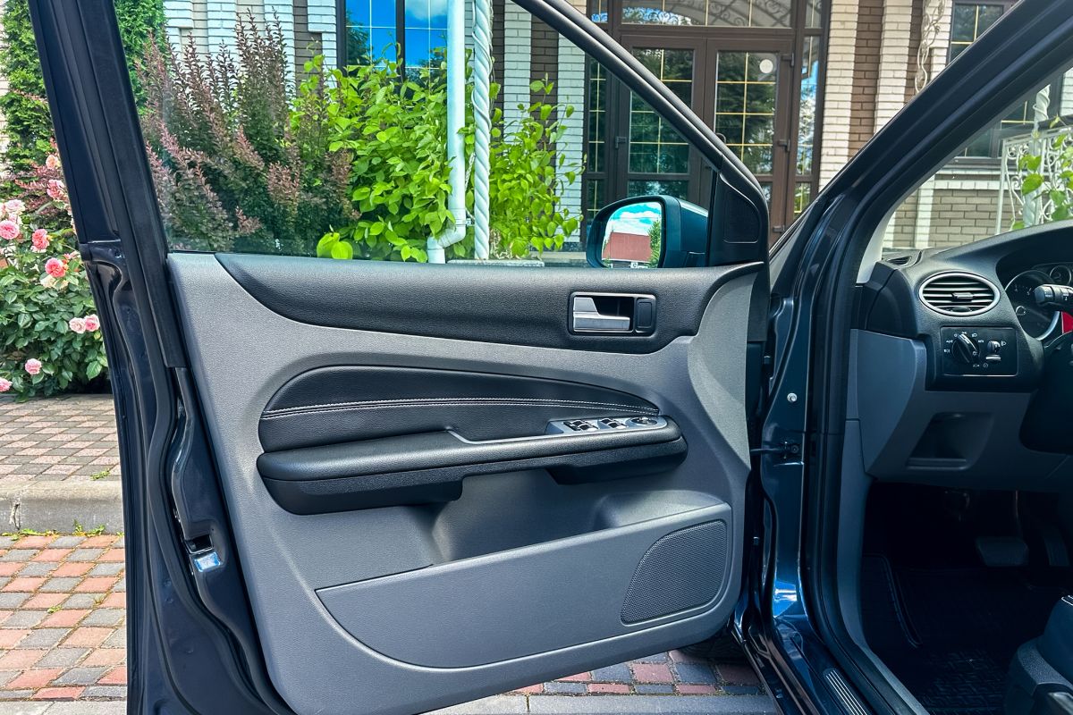 Car door interior with power window controls showing auto glass in proper alignment, representing solutions for when car windows stop rolling.