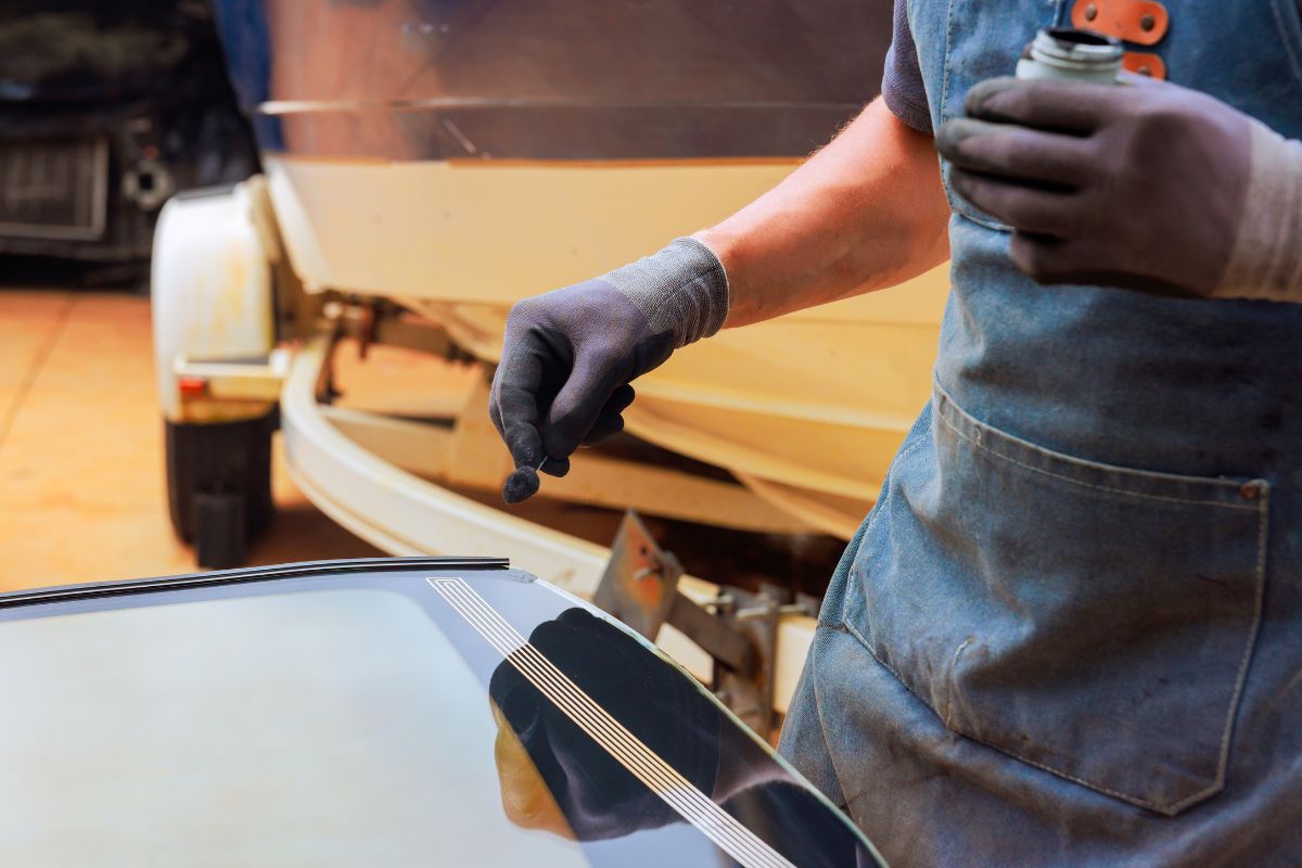 Windshield technician applying sealant to auto glass to protect against seasonal changes in Wisconsin