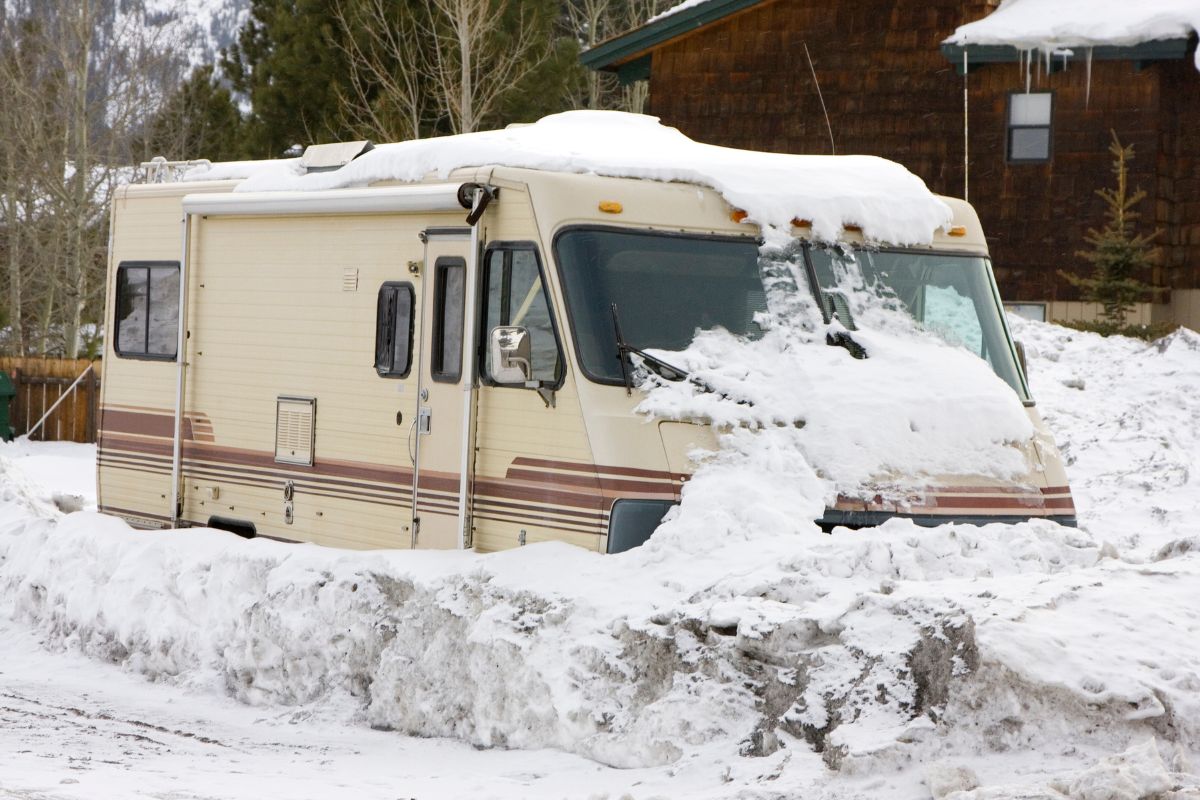 Snow-covered RV parked in Wisconsin with windshield protected against winter weather damage.