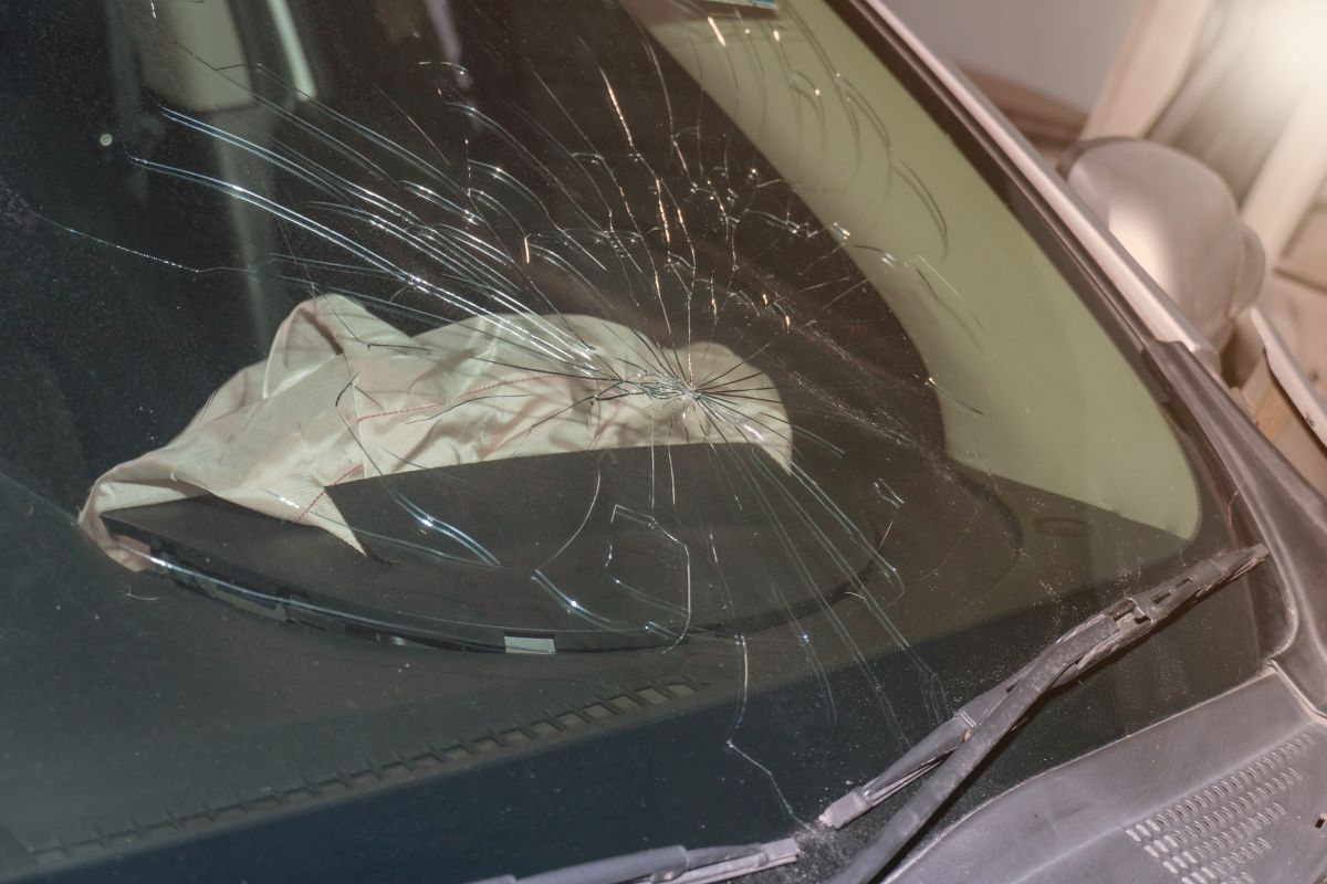 Cracked windshield on a vehicle interior with deployed airbag, showing significant glass damage often seen in Oconomowoc’s lake-edge neighborhoods.