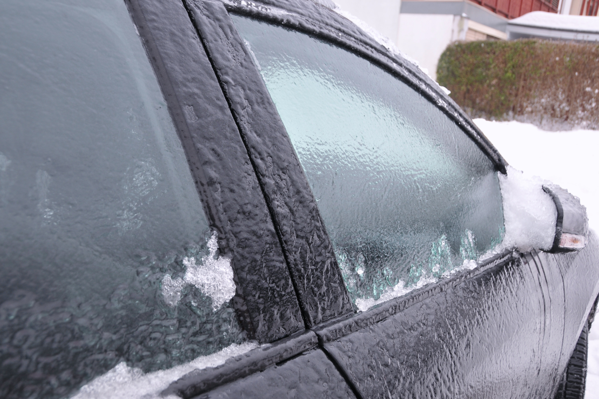 Car windshield and rear window covered in frost and snow on a cold Wisconsin morning, showing frozen car windows that need safe defrosting.