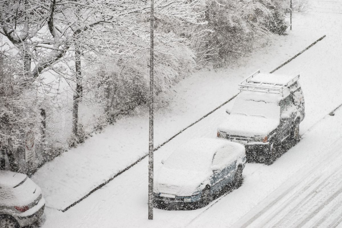 Cars covered in heavy snowfall on a Wisconsin street, showing winter driving conditions that often lead to new year auto glass problems like chips and cracks.