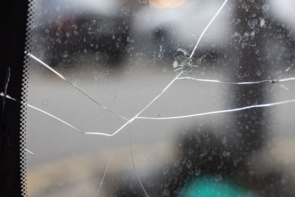 Close-up view of a cracked windshield caused by a rock impact showing multiple spreading fractures.