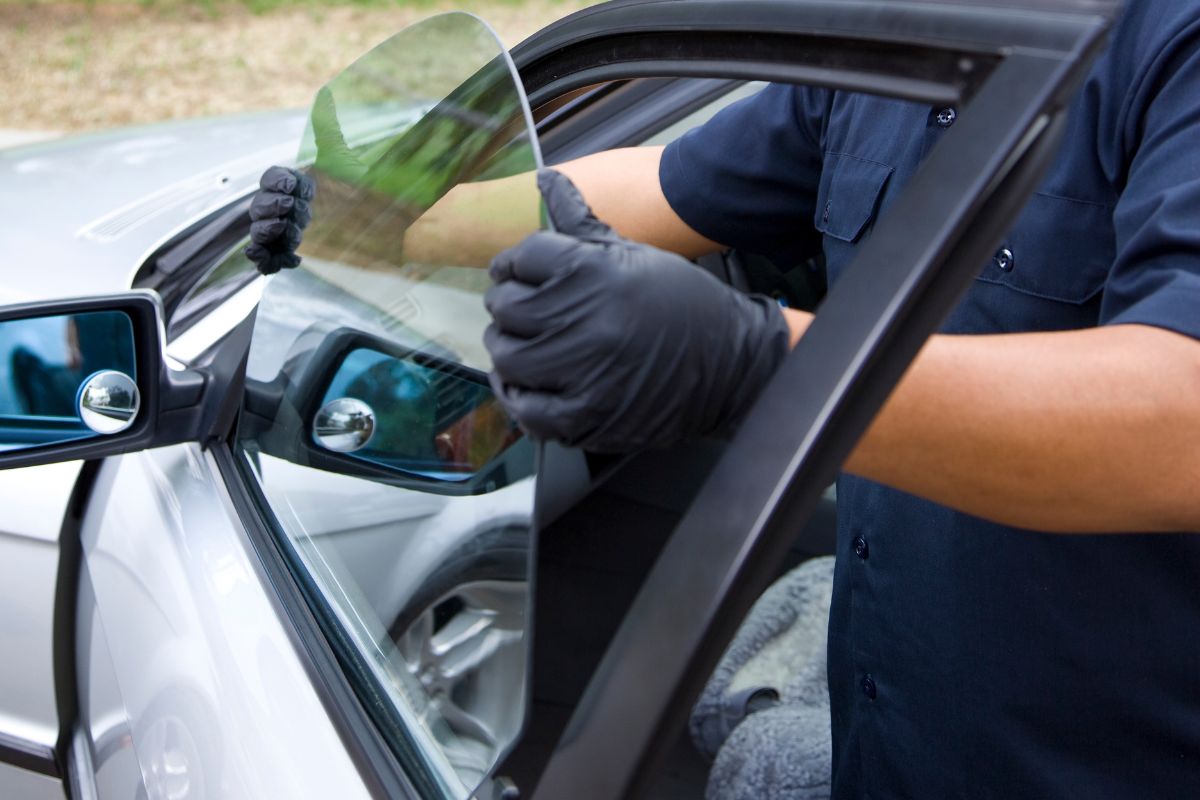 Technician performing power window repair on a vehicle door, removing damaged car window glass during mobile auto glass service in Wisconsin