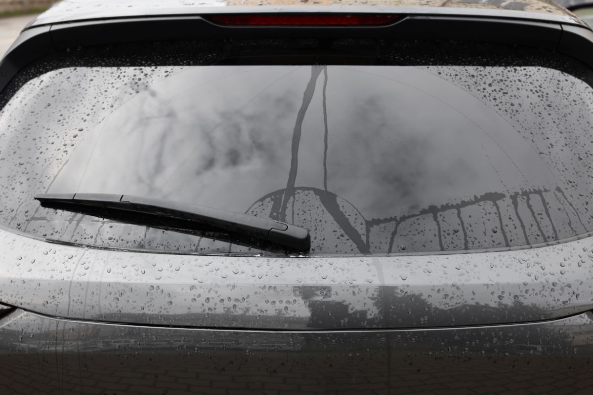 Rear car back glass with visible cracks and water streaks, showing signs that back glass replacement may be needed in Wauwatosa.